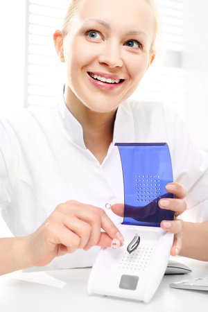 Audiologist shows how to use the dryer for hearing aidsの写真素材