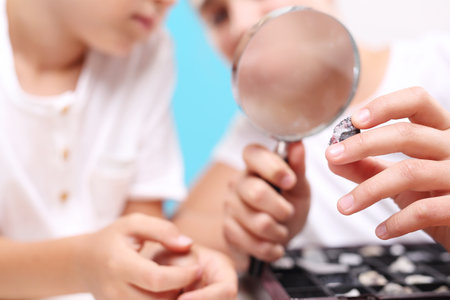 Mineral. Two children, a girl and a boy watching through a magnifying glass stones from his collection of rocks.の写真素材