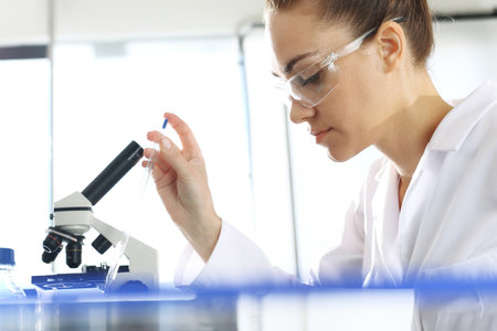 Chemist examine the samples under a microscope.の写真素材