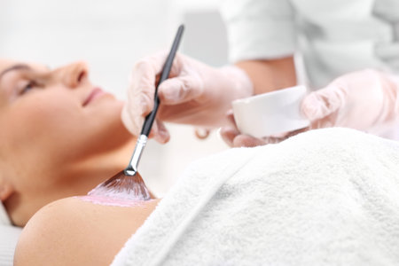 Face mask with algae applied to the neckline. The woman in the beauty salon, beautician brush mask is applied to the neckの写真素材