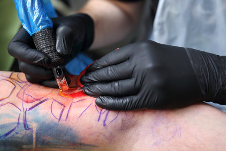 The tattoo parlor. A tattoo artist tattooing color tattoo on his hand manの写真素材