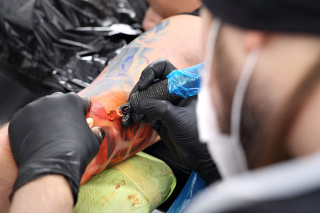 Tattooer tattooing color tattoo on his hand manの写真素材