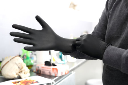 Male tattoo artist assumes black latex glovesの写真素材