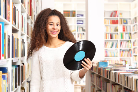 Black disc, vinyl publication of an album music. A young woman in an antique shop buys analogue...