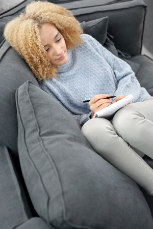 Relax on the sofa. Female recorded in his notebookの写真素材