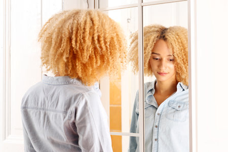 Sad girl looks at himself in the mirror