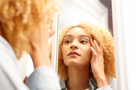 The aging of the skin. Woman looks in the mirror watching for the first signs of aging.の写真素材