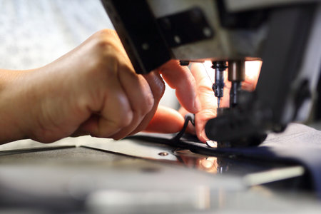 The woman sewing on the machine. The production plant, sewing clothes by seamstresses on the sewing machineの写真素材