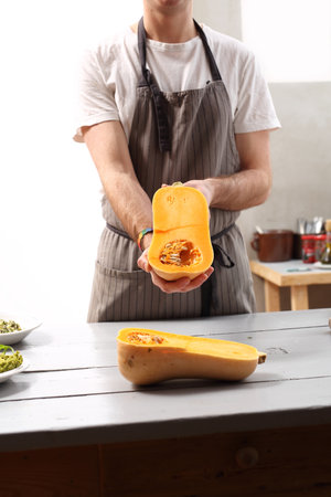 Pumpkin in the kitchen. The cook holds in his hand mature butternut squash.の写真素材