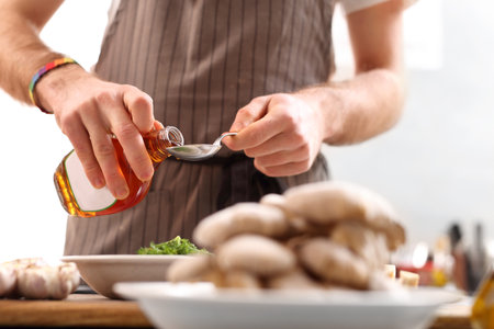 Maple syrup, and sweet Addition to cooking. The cook pours maple syrup on a spoon.