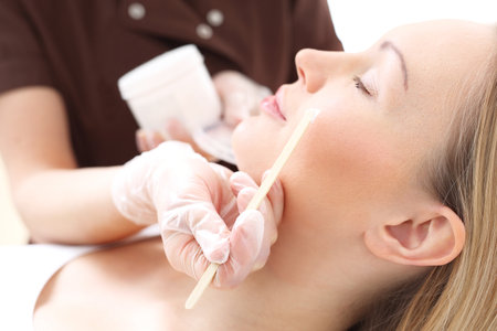 Facial mask. The woman in the beauty salon, beautician applied with a brush to the face mask.の写真素材