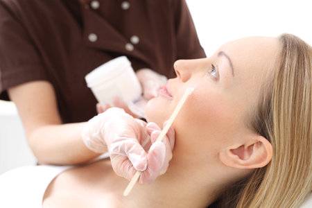 Facial mask applied with a spatula. The woman in the beauty salon, beautician applied with a brush to the face mask.の写真素材