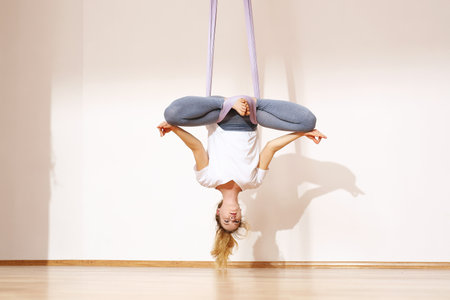 Yoga exercises. A woman is practicing yoga on a hose, aerial yogaの写真素材
