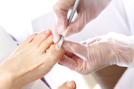 Nail cleaning in the beauty salon. Beautician performs a pedicure, cleans and cuts fingernails at the feetの写真素材