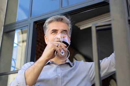 Aroma of wine. A man smells a bouquet of red wine given by a waiter.の写真素材