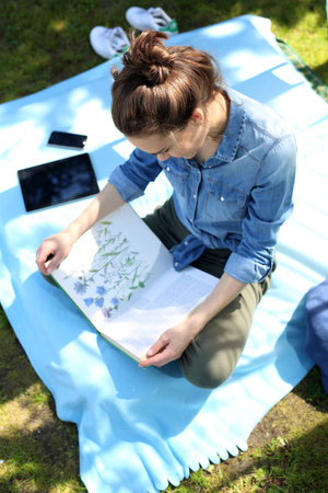 A beautiful young woman relaxing while reading a book while sitting on a blanket.の写真素材