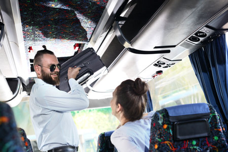 Suitcase. A handsome man helping a woman put her luggage on a shelf in a coach.の写真素材