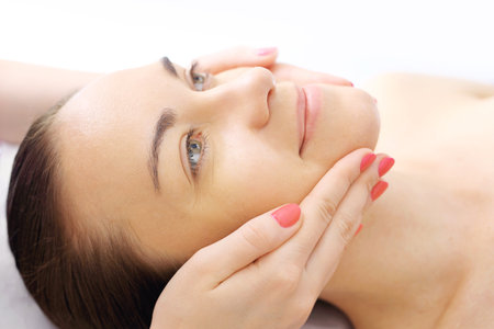 Relaxing facial massage. Woman in beauty parlor during facial massage.の写真素材