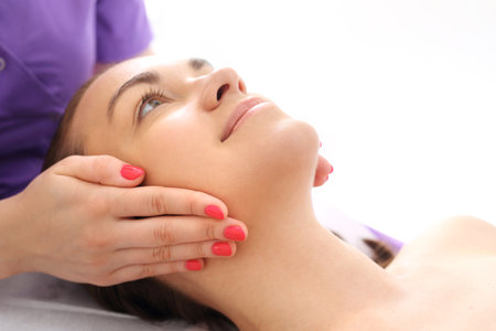 Professional face massage. Woman in beauty parlor during facial massage.の写真素材