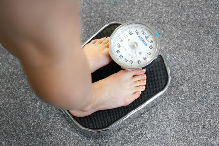 The correct weight of the body. Woman weighs on bathroom scales.の写真素材