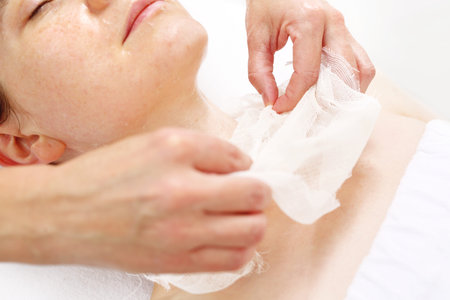 Skin care in the clinic of aesthetic medicine. The beautician removes the bandage from the face of the patient.の写真素材
