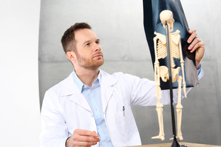 Orthopaedist. A doctor in the office is watching an x-ray of a patient.