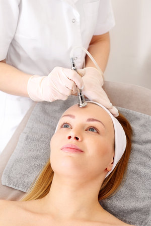 Acne treatment, oxygen infusion in cosmetics. A woman in a beauty salon during a care treatment using active oxygenの写真素材
