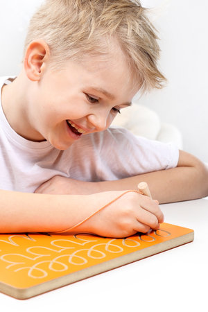 Motor motivation training. Smiling boy practicing writing letters.の写真素材