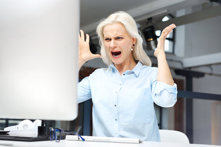 Nerves and anger at work. Furious young woman is irritated at workの写真素材