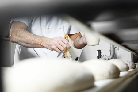 Baker, pastry chef prepares the dough for baked goodsの写真素材