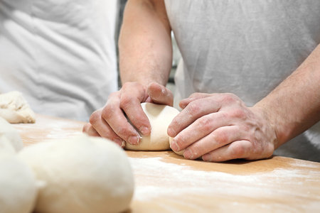 Kneading the dough. Baker, pastry chef prepares the dough for baked goodsの写真素材