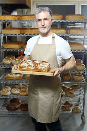 Baker. A handsome baker with a loaf of fresh bread.の写真素材