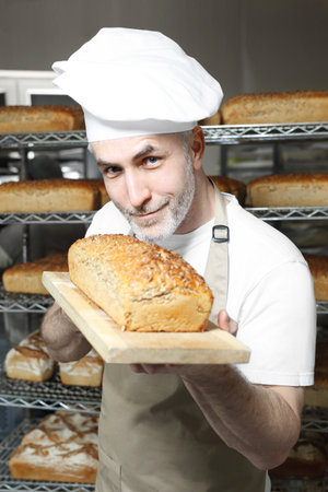 Bread. A handsome baker with a loaf of fresh bread.の写真素材