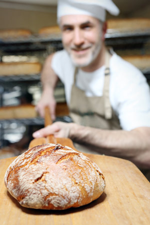 Bread. A handsome baker with a loaf of fresh bread.の写真素材