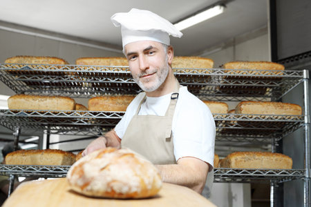 Baker in the bakery. Bread. A handsome baker with a loaf of fresh bread.