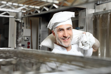 Baker. Smiling, happy cook carries a sack of flourの写真素材