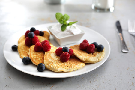 sweet breakfast. A portion of tasty pancakes with berries, served with yoghurt sauceの写真素材