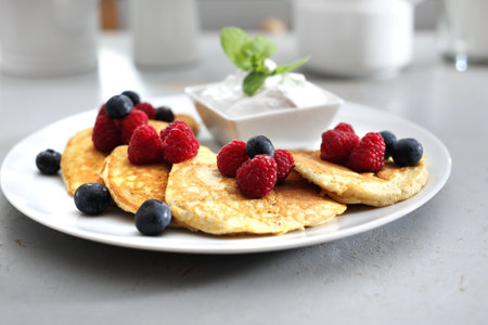 Pancakes with raspberries and blueberries. A portion of tasty pancakes with berries, served with yoghurt sauceの写真素材