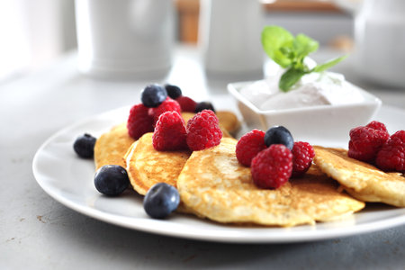 Breakfast. A portion of tasty pancakes with berries, served with yoghurt sauceの写真素材