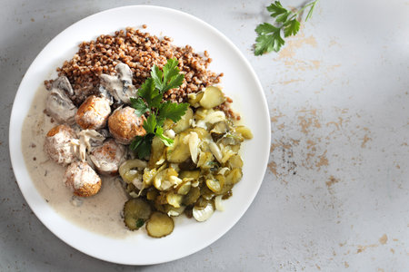 Dinner meal. Meatballs in a cream sauce with buckwheat and a cucumber salad.の写真素材
