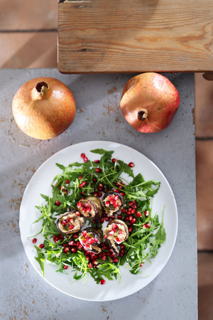 Healthy eating. Eggplant roulades with cheese served with pomegranate on rocket lettuce.の写真素材