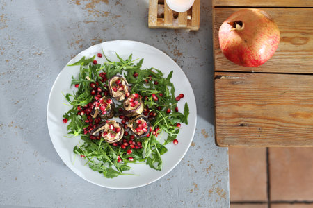 Veg salad with eggplant. Eggplant roulades with cheese served with pomegranate on rocket lettuce.の写真素材