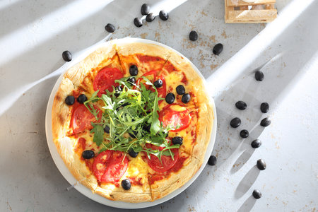 Pizza with tomatoes, black olives, arugula.の写真素材