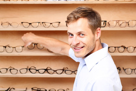 Optical salon. The man chooses the spectacle frames in the optical salonの写真素材