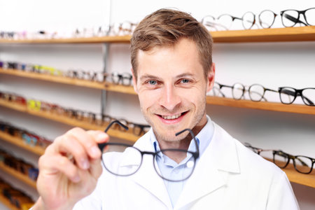 Optical salon. The man chooses the spectacle frames in the optical salonの写真素材
