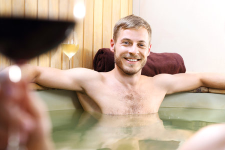 Hot tub bath. A relaxed, smiling young man relaxing in a tub with water.の写真素材