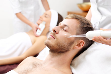 Spa for two. Man and woman in a beauty salon on face skin care treatment.の写真素材