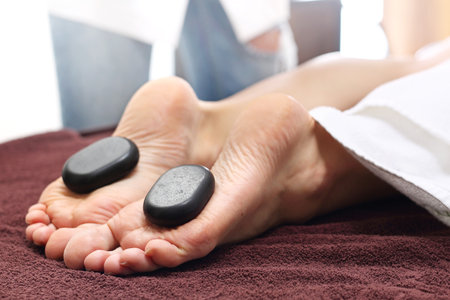 massage with stones. Female feet with basalt stones, relaxing in the spa salon.の写真素材