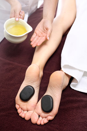 Female feet with basalt stones, relaxing in the spa salon.の写真素材