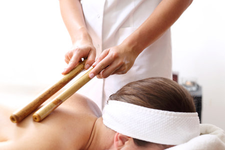 Massage with bamboo chopsticks. The masseur massages the body using bamboo sticks.の写真素材